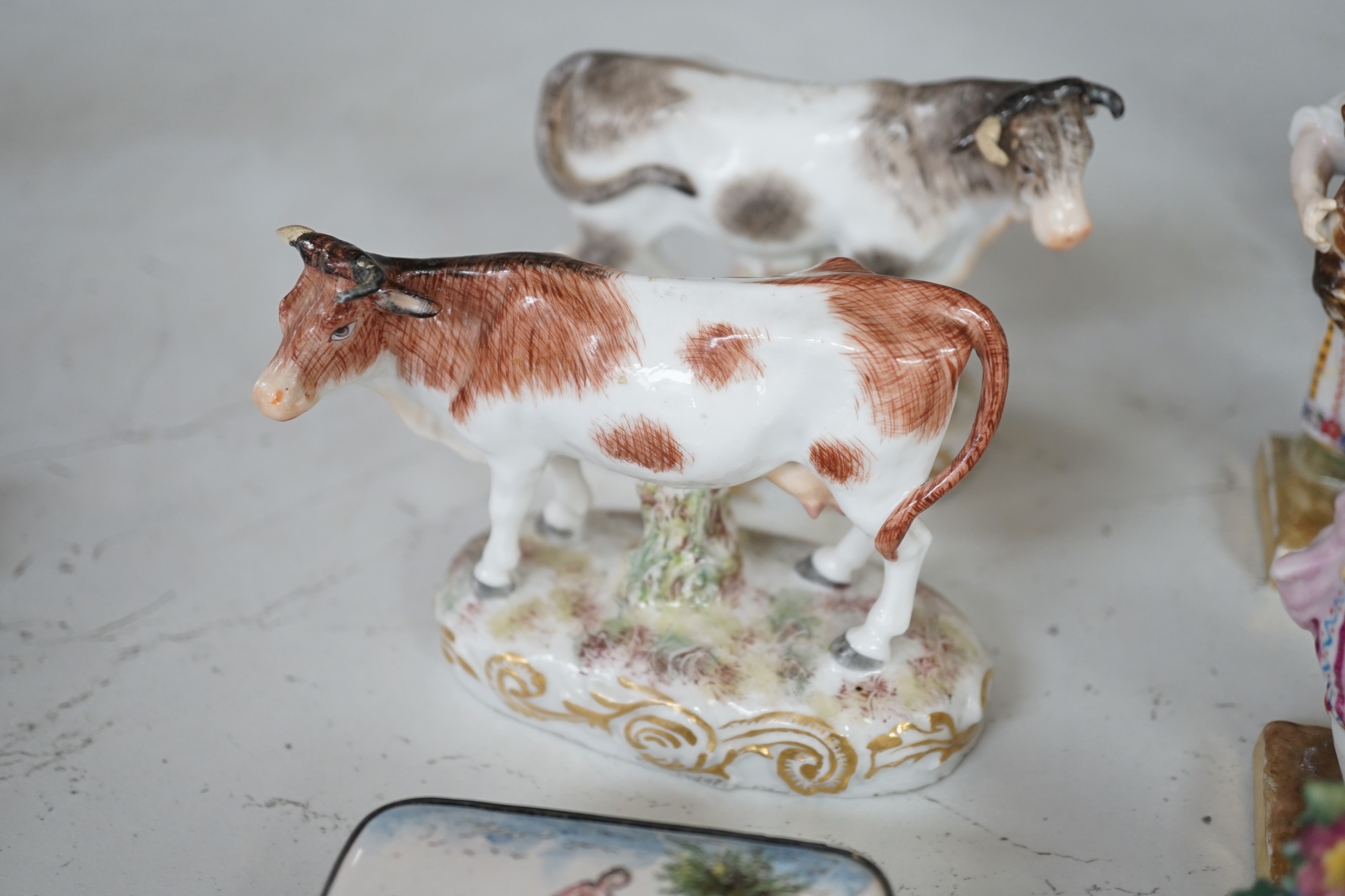 A pair of Hochst porcelain models of cows, 10.5cm long, a lidded box and other Continental figures